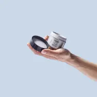 Une main tient le pot de ma crème nuit ouvert