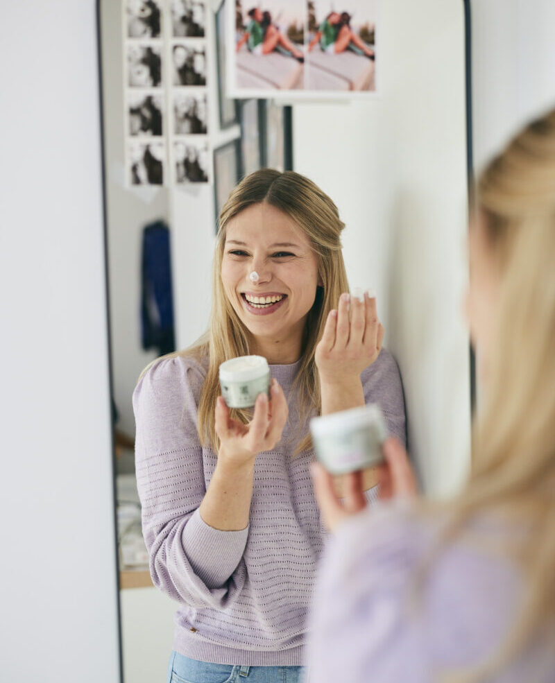 Une jeune femme sourit en appliquant la crème jour FORMY