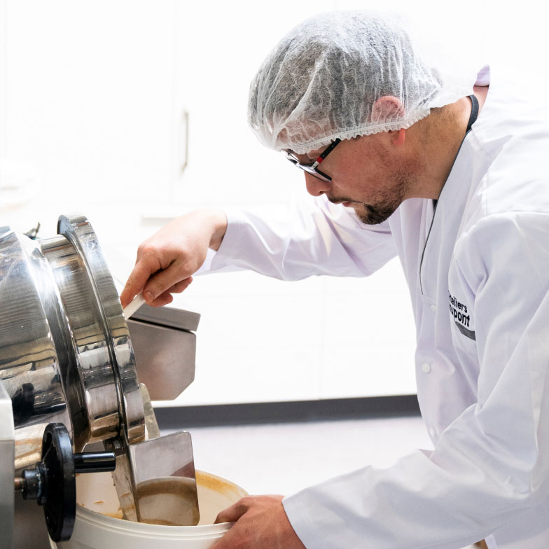 Travailleur versant du jus d'une cuve dans un seau