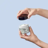 Une main qui tient le pot de ma crème nuit et une autre main ouvre le pot