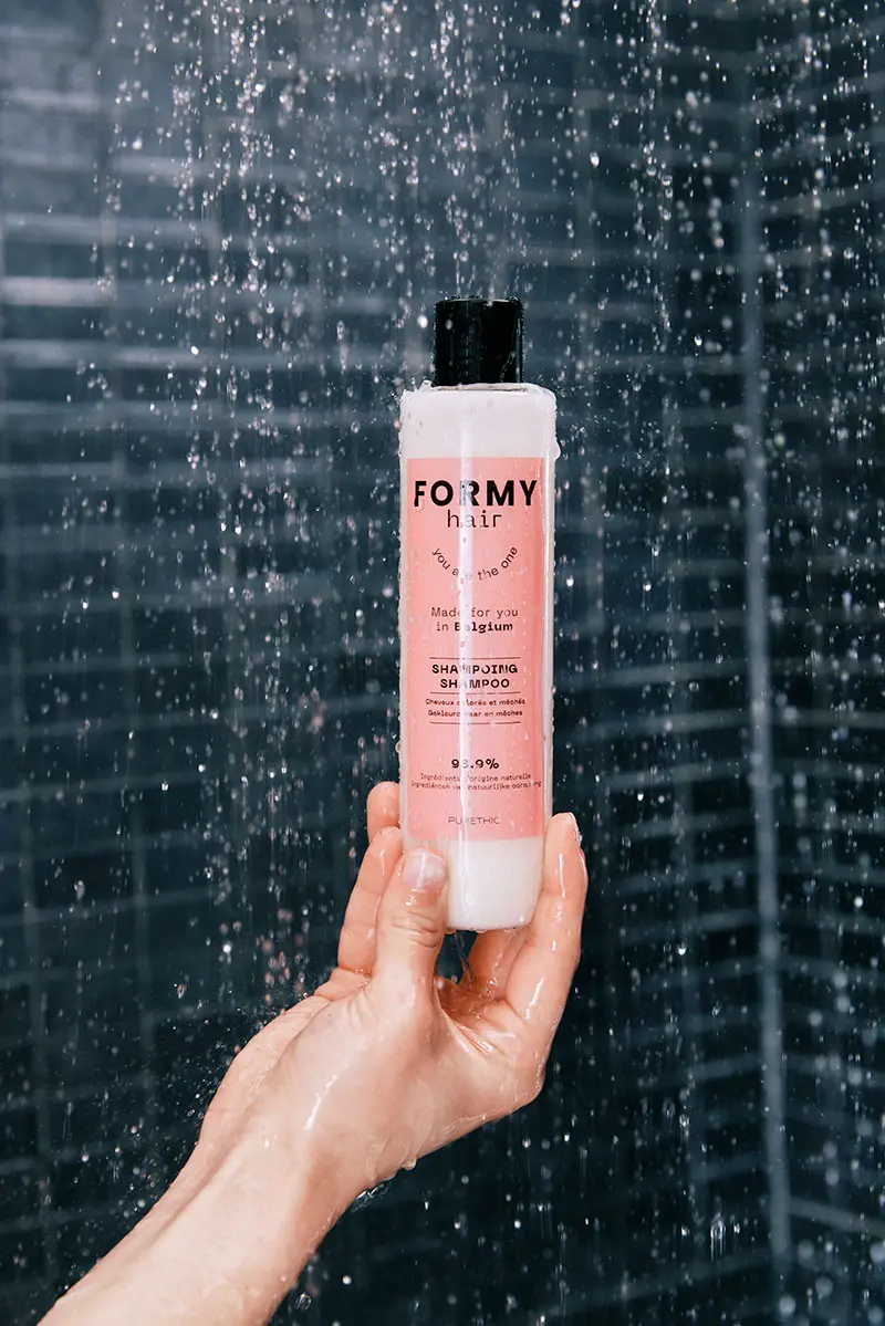 Formy_lifestyle-25 Main tenant verticalement un flacon de shampoing liquide pour cheveux colorés et méchés sous la douche qui coule un flac