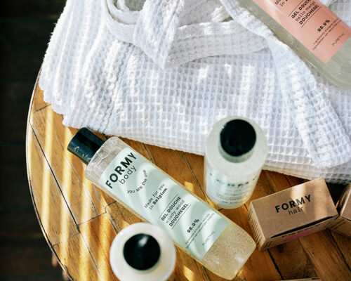 Flacons de gels douche et shampoing liquide avec des après shampoings solide posés sur une table