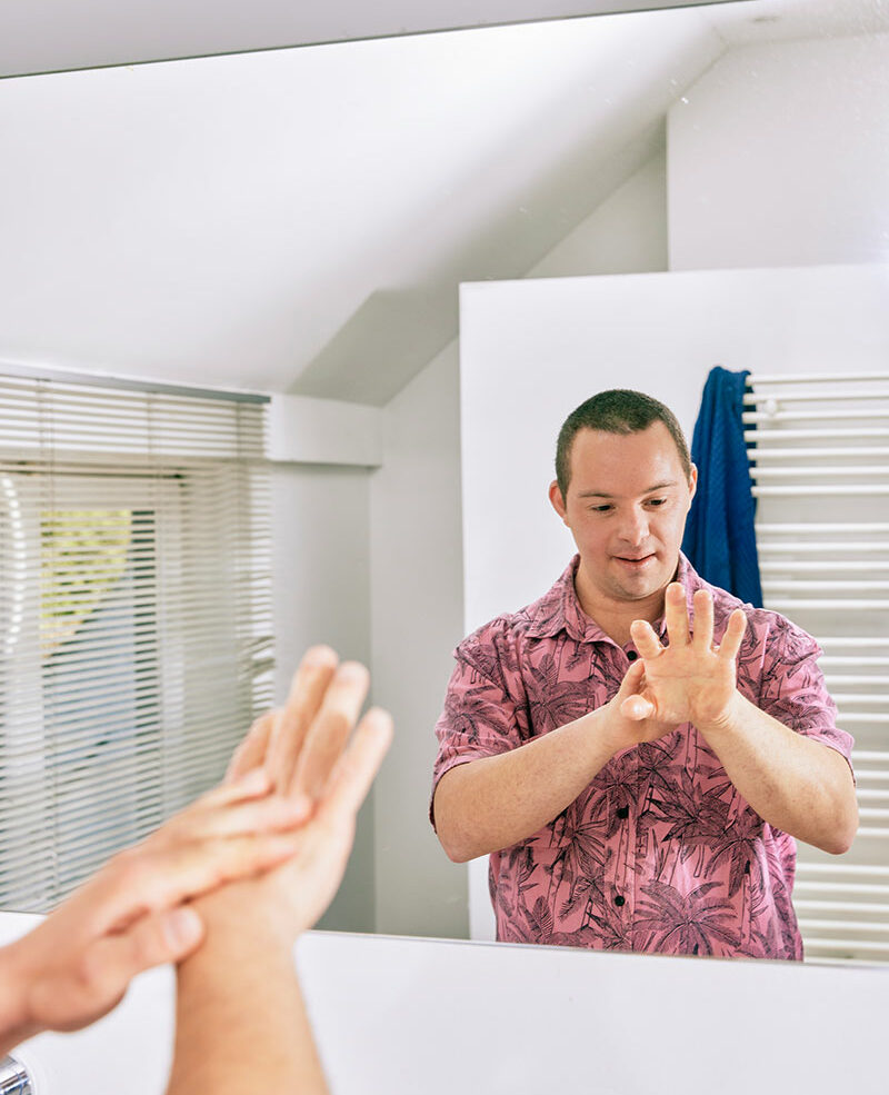 Homme dans le miroir s'apppliquant de la crème sur les mains