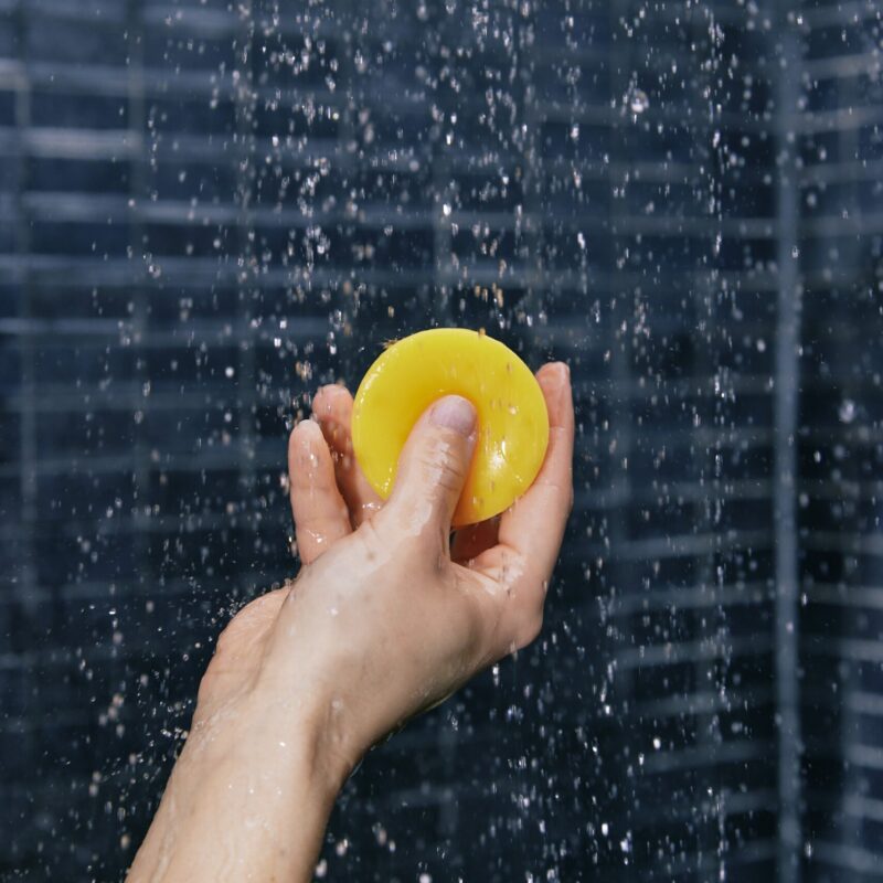 Main tenant un après-shampoing solide sous la douche