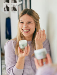 Une jeune femme blonde qui s'applique de la crème visage.