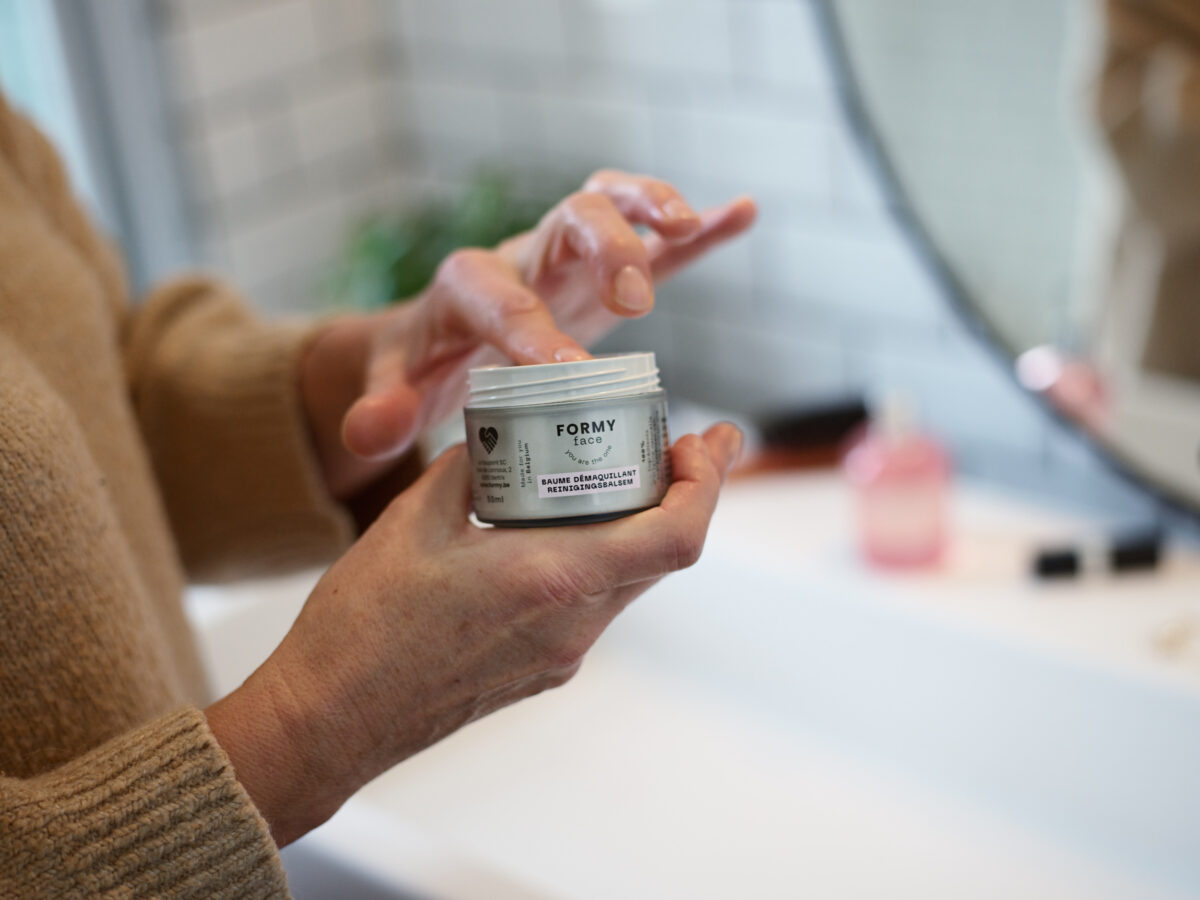 FOR_Baume démaquillant Femme prenant une noisette de baume démaquillant dans son packaging