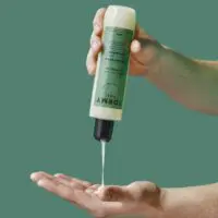 Une main verse mon shampoing pour homme dans une autre main
