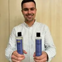 Un homme tient deux flacons de gel douche Berrylicious avec deux logos d'associations