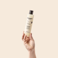 Une main tend un flacon de mon shampoing liquide tous types de cheveux