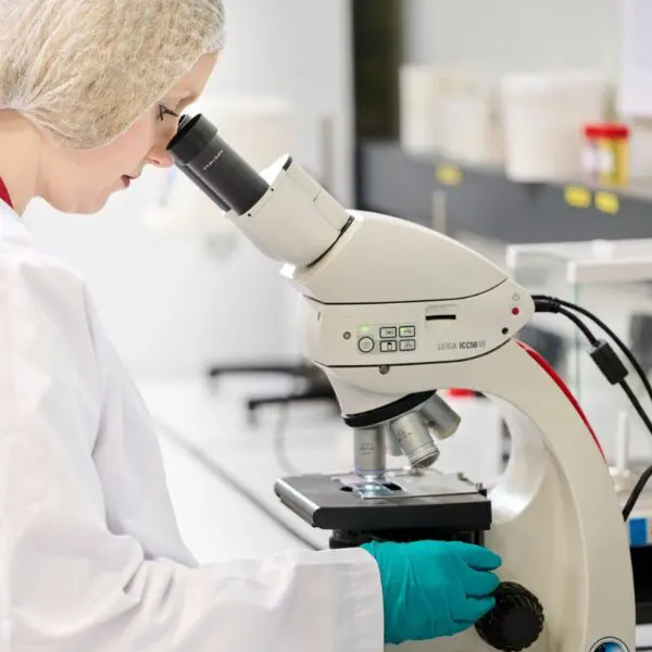 Ma cosmétologue en train d'utiliser son microscope