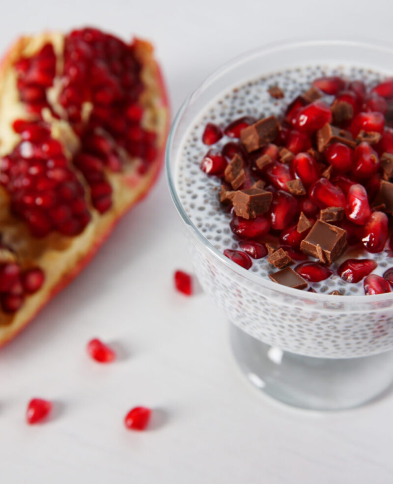 Chia seeds pudding with pomegranate grains and chocolate chips in glass saucer on white background Chia seeds pudding with pomegranate grains and chocolate chips in glass saucer on white background